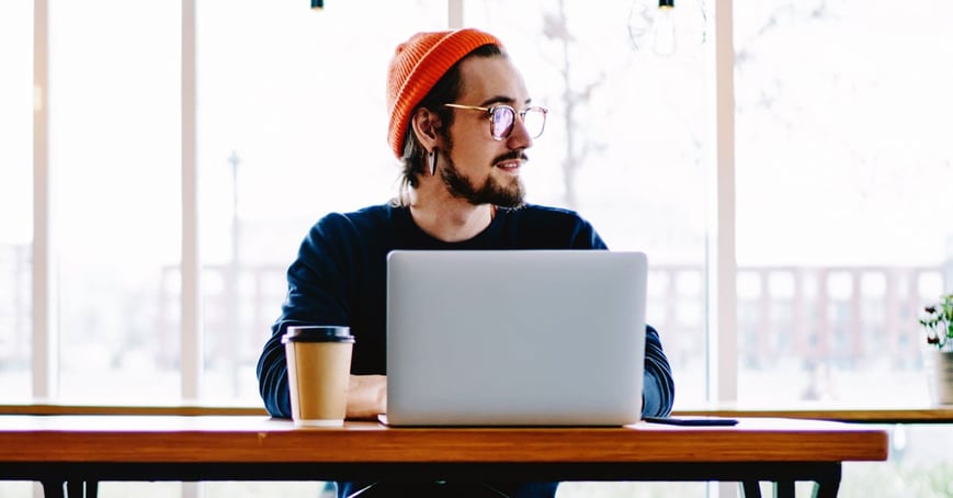 Man typing on laptop in coffee shop