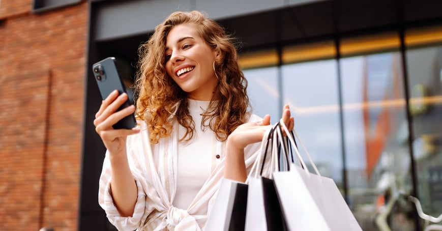 Woman holding cell phone and shopping bags