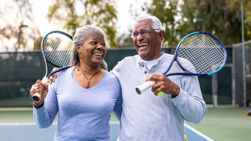 Retired couple playing tennis together 