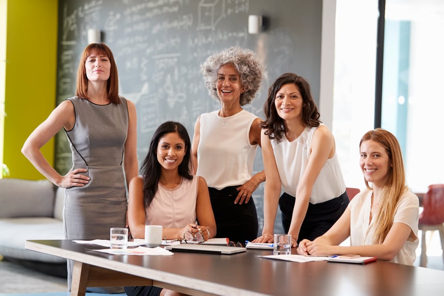 Business women smiling around a table