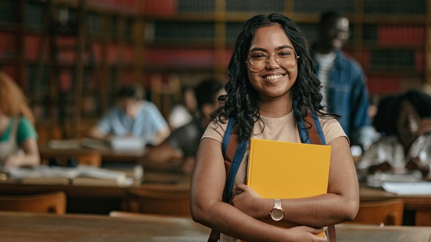 college student in library holding books