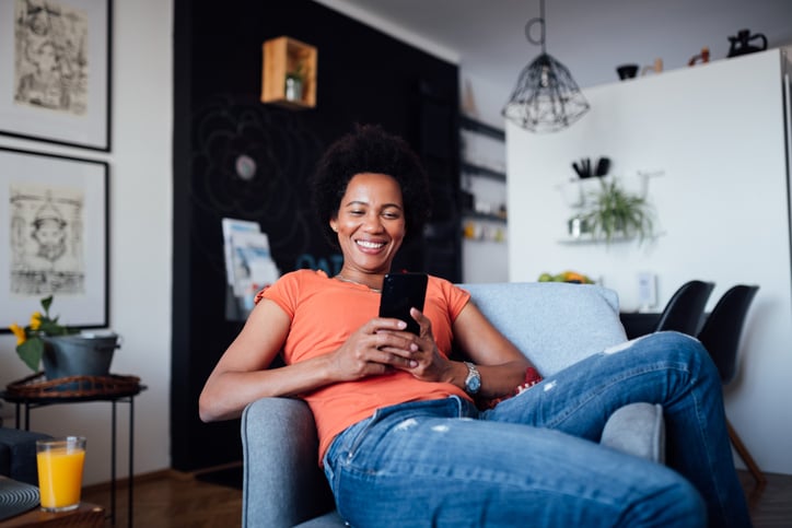 Young woman using her phone while relaxing at home