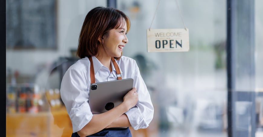 Business owner standing in front of open sign