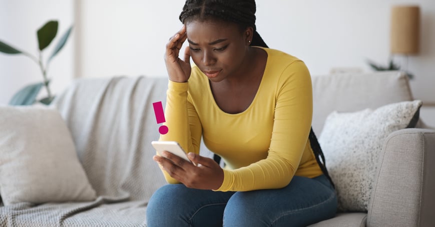 Woman looking at phone, distressed by phishing scam